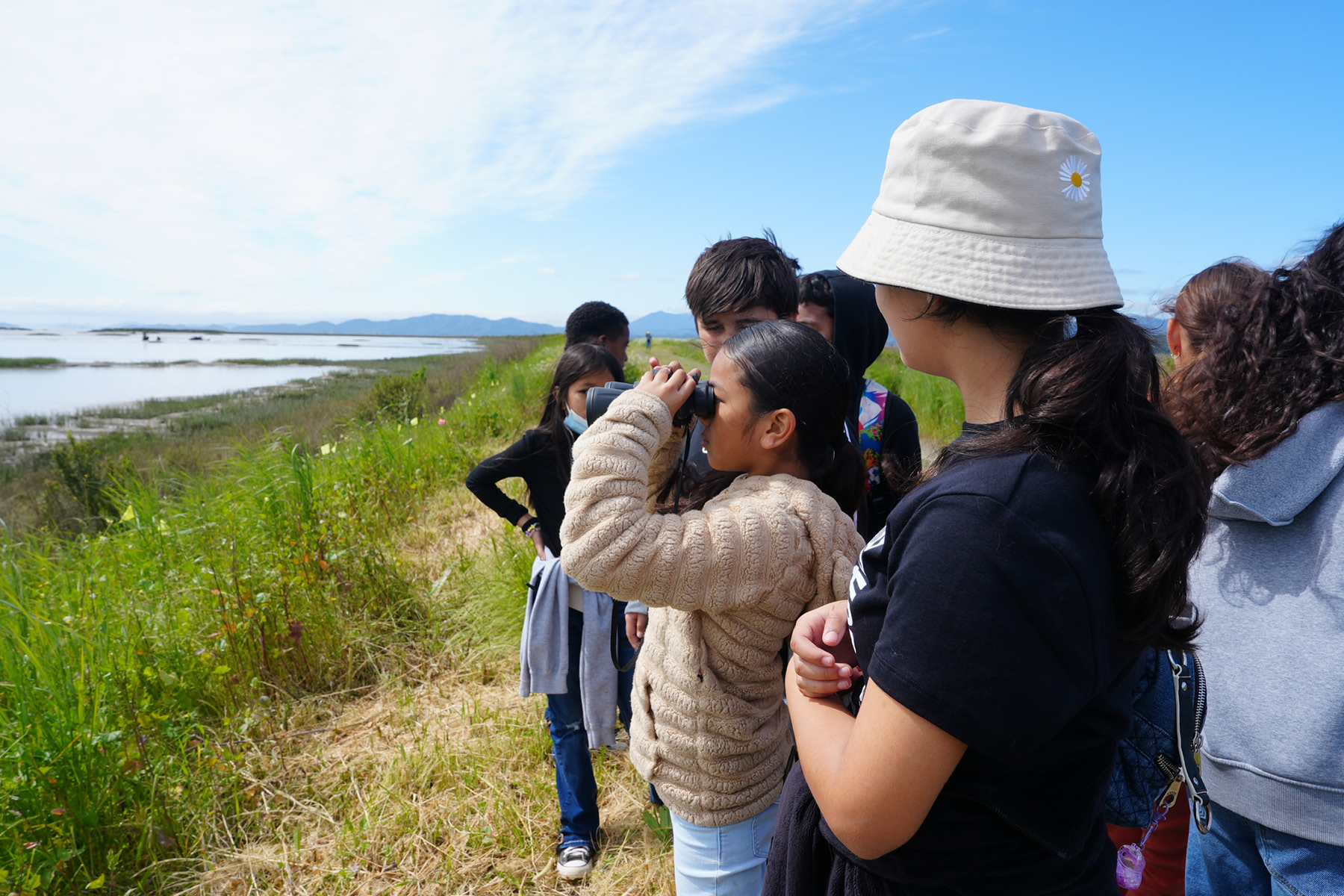 Escolares miran el agua con prismáticos