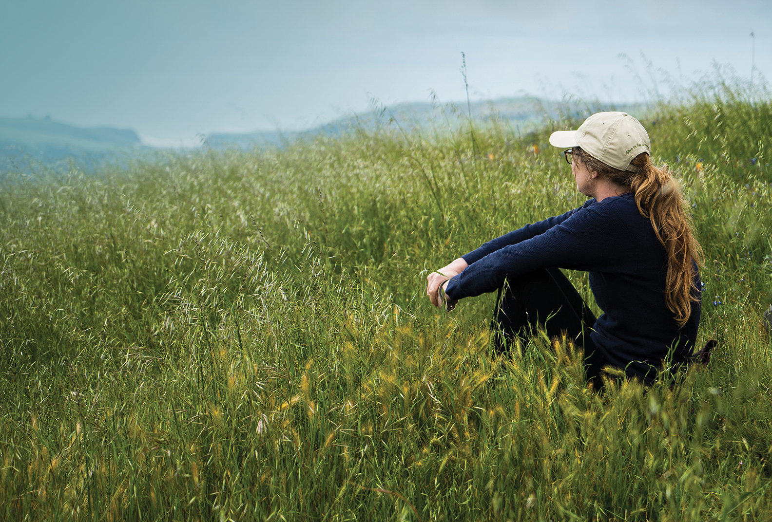 Hiker sits to rest on a grassy hillside