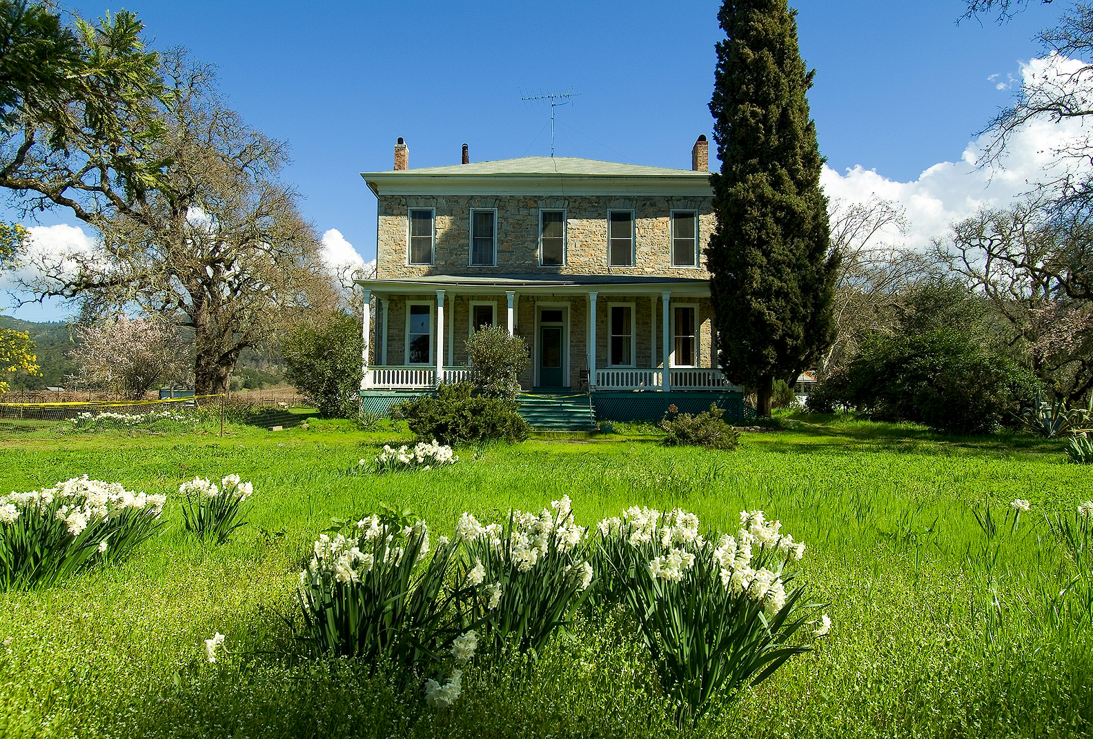 Historic stone home in Glen Oaks Ranch with wildflowers in the foreground