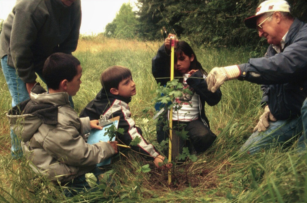 Kids and adults planting a tree.