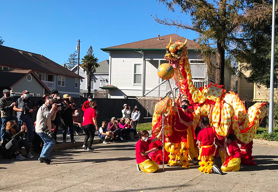 Chinese dragon puppet with performers in urban setting.