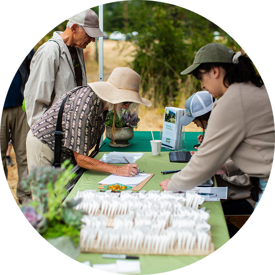 Miembros del equipo de Land Trust saludando a la gente en un acto.